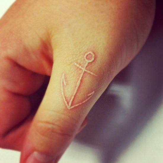 Small anchor tattoo on Yasmin's left forearm.